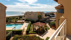 Edifício residencial com piscina, pátio e vista para o mar.
