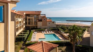 Hotel com piscina, vista para a praia e uma palmeira.