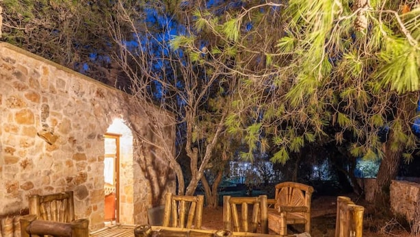 Un espacio de estar al aire libre con paredes de piedra y mobiliario de madera.