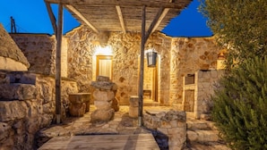 Un patio de piedra con un banco de madera, una mesa de piedra y una estructura de pérgola.