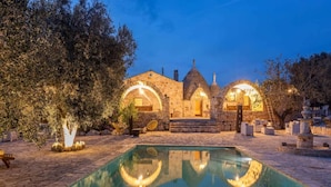 Un edificio de piedra con arcos y una piscina al frente.