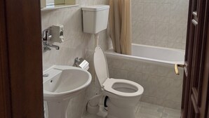 Et badeværelse med toilet, håndvask og badekar.