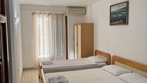 Et hotelværelse med to senge, et skab, en aircondition og et billede på væggen.