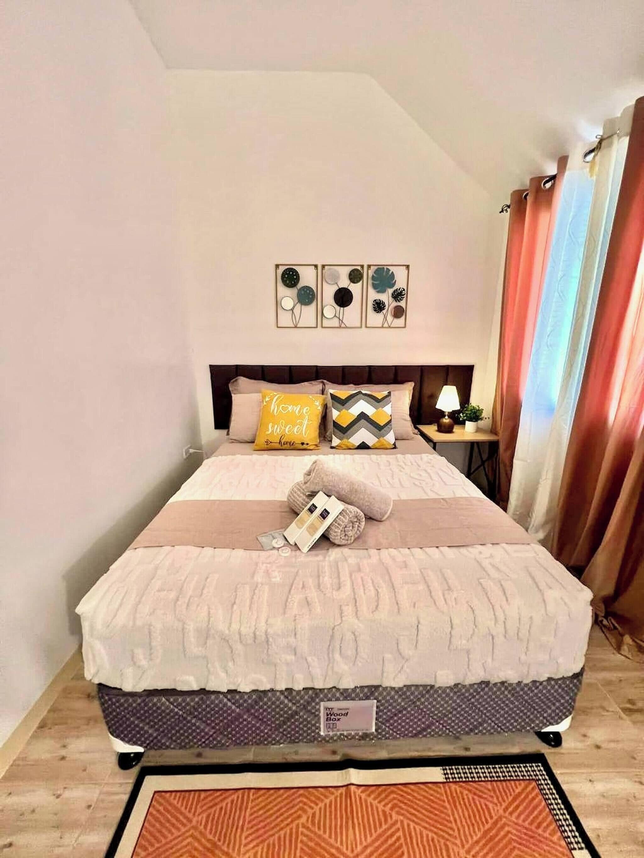 A bedroom with a bed, pillows, a nightstand, a lamp, and a wall art piece.
