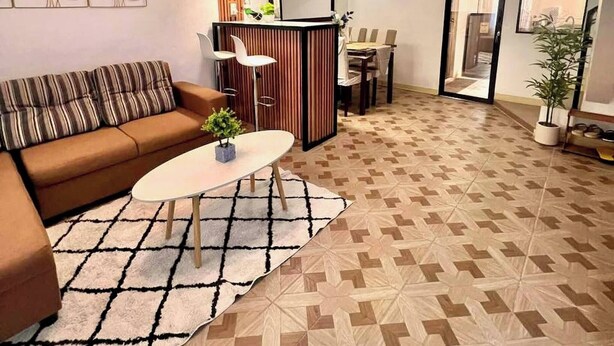 Una sala de estar moderna con sofá, mesa de centro y comedor con sillas.