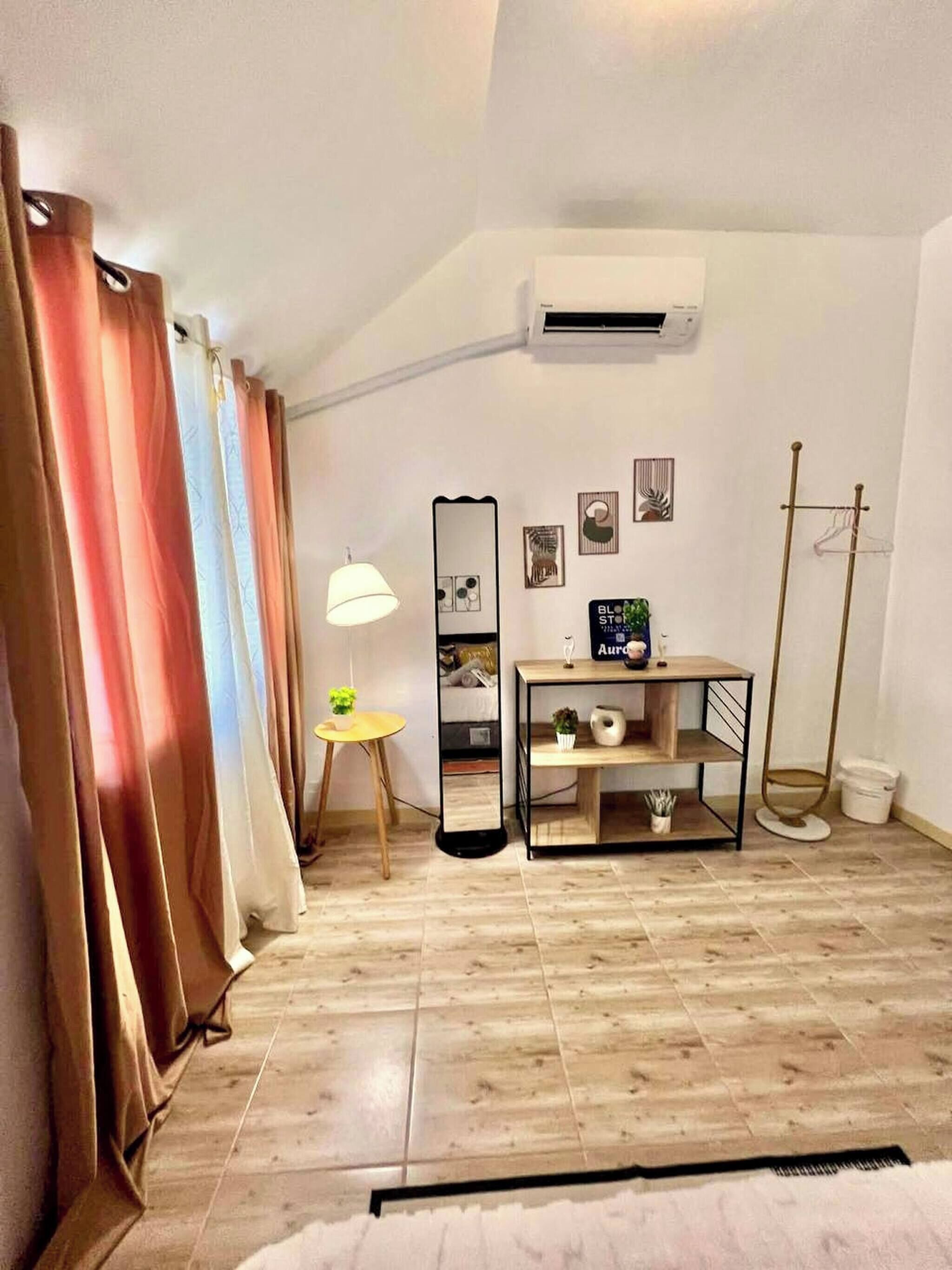 Une chambre comprenant un lit, une table de chevet, une lampe, un miroir et un climatiseur fixé au mur.