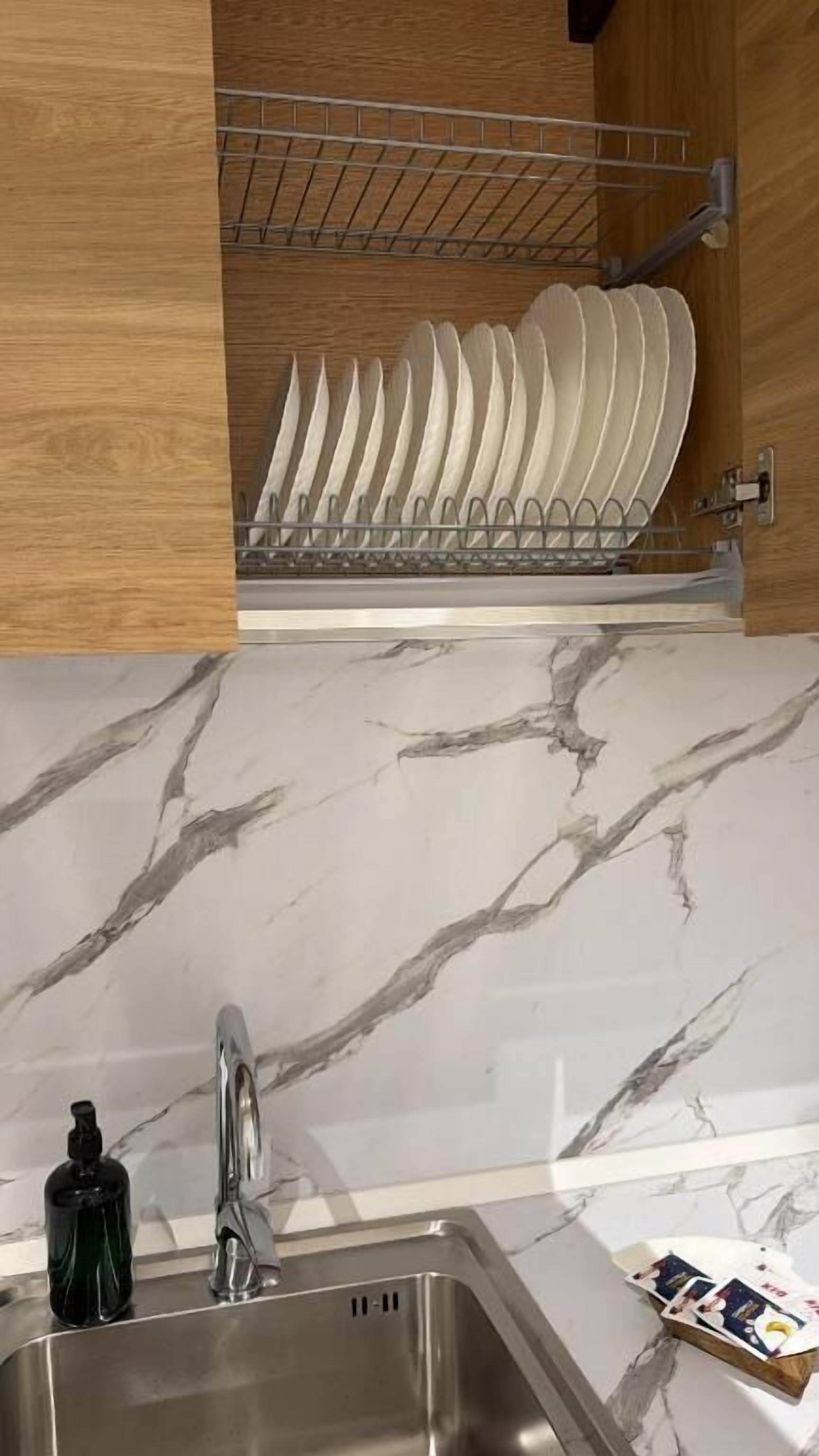 Una cocina con escurreplatos, pileta y encimera de mármol.