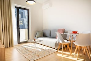 A modern living room with a sofa, a small table, and chairs. - Barrikada - E Apartments (Tirana)