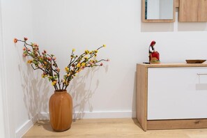 A corner of a room with a wooden cabinet, a vase with flowers, and a figurine on the cabinet. - Barrikada - E Apartments (Tirana)