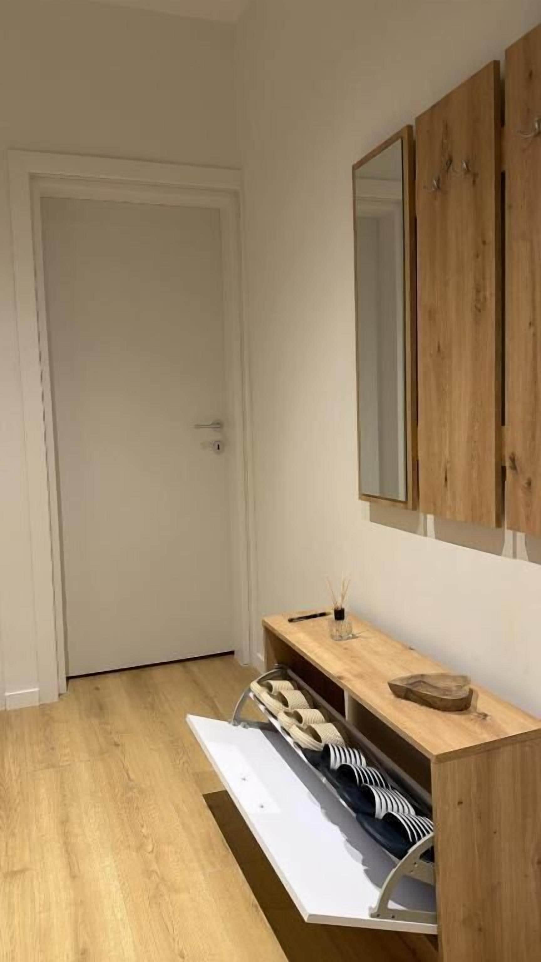 Ein Flur mit Holzschrank, Spiegel und Schuhablage.