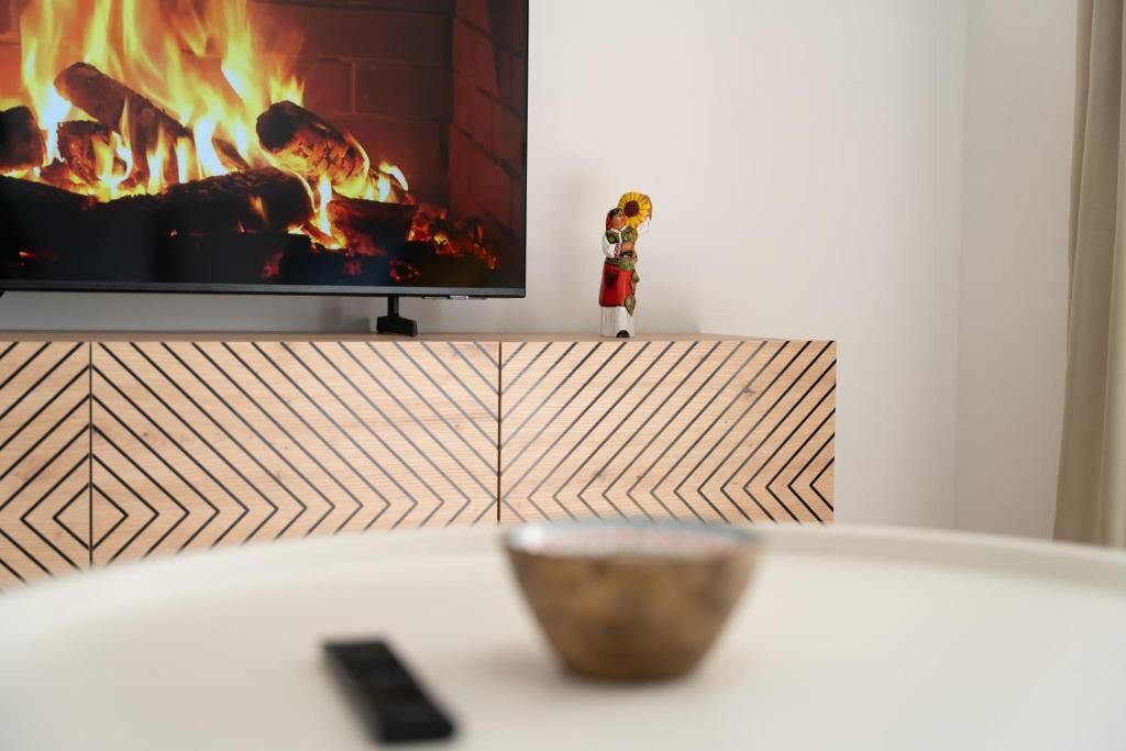 Un téléviseur diffusant une image de feu, une figurine décorative et une télécommande, le tout posé sur une table.