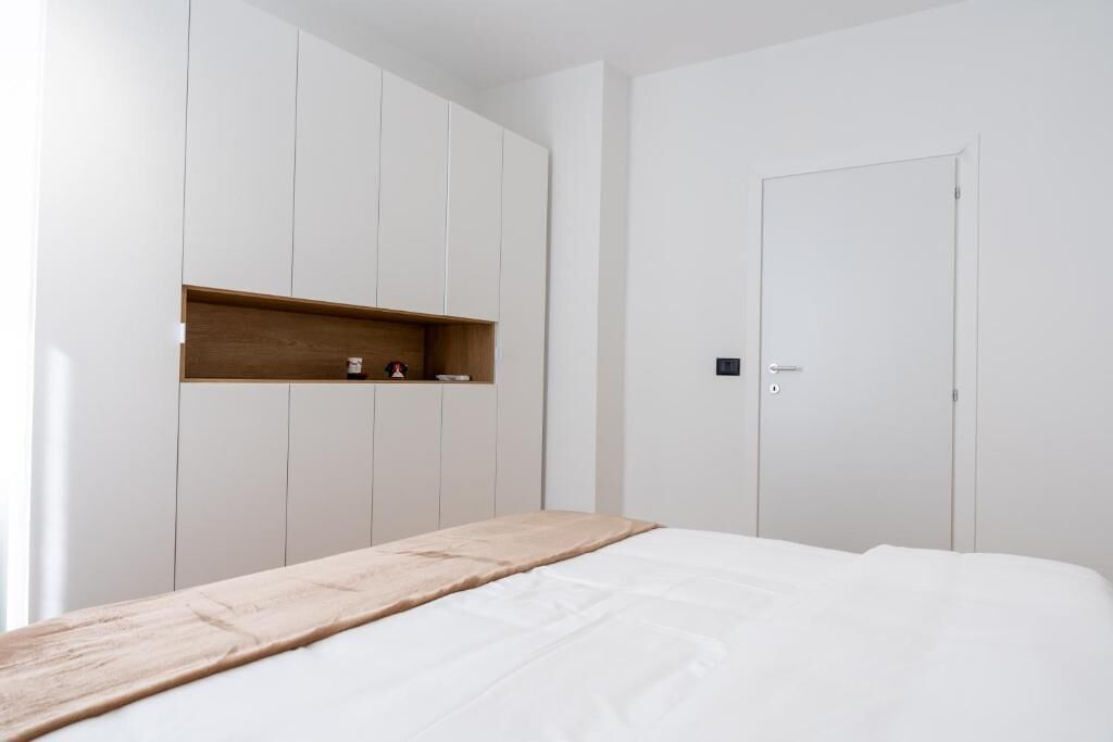 Ein Schlafzimmer mit einem Bett, einer Holzablage und einem weißen Kleiderschrank.