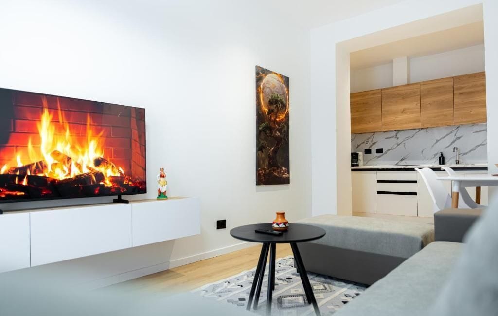 A modern living room with a fireplace, a kitchen with wooden cabinets, and a dining area.