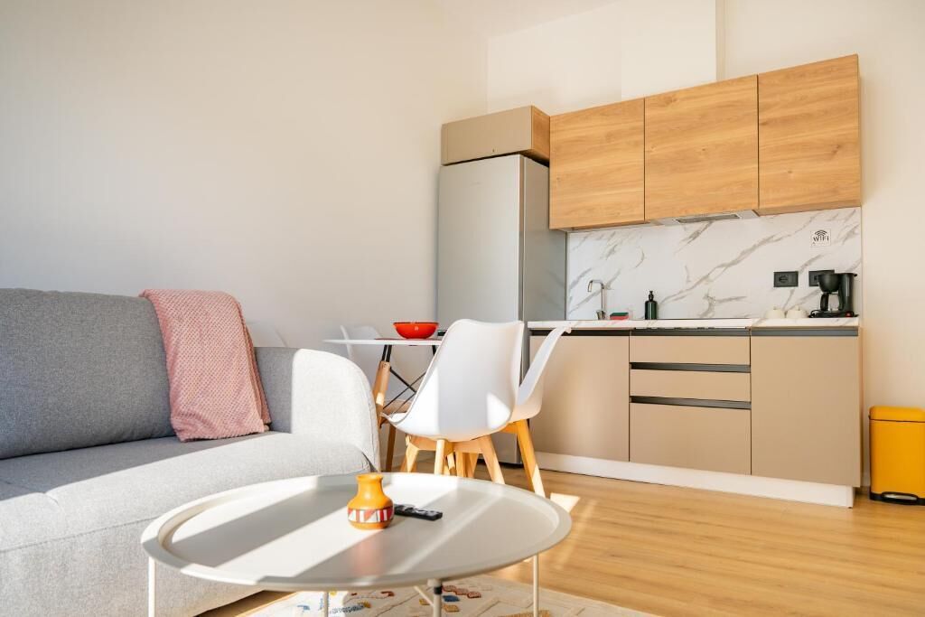 A modern living room with a sofa, a coffee table, and a dining area with chairs and a table.