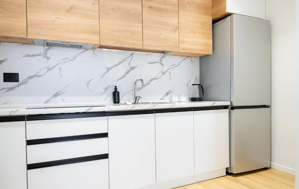 Eine moderne Küche mit weißen Schränken, einer Marmor-Spritzschutzleiste und einem Edelstahl-Kühlschrank.