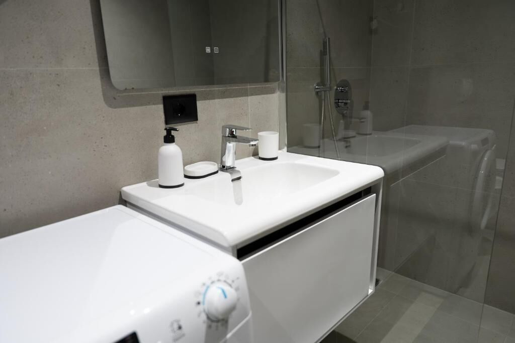 Een moderne badkamer met een wit wastafelmeubel, spiegel en douche.