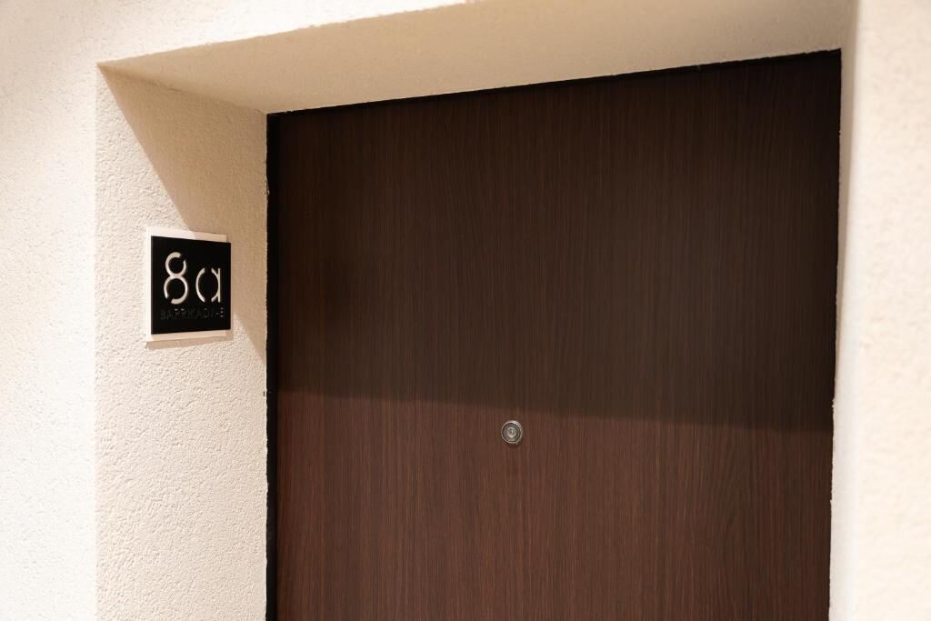 Een donker houten deur met een klein, wit bord erboven.