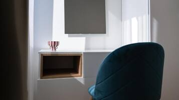 A room with a window, a blue chair, and a small wooden shelf with a red and white striped object.