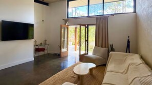 A spacious living area with a sofa, a small table, and a TV mounted on the wall.