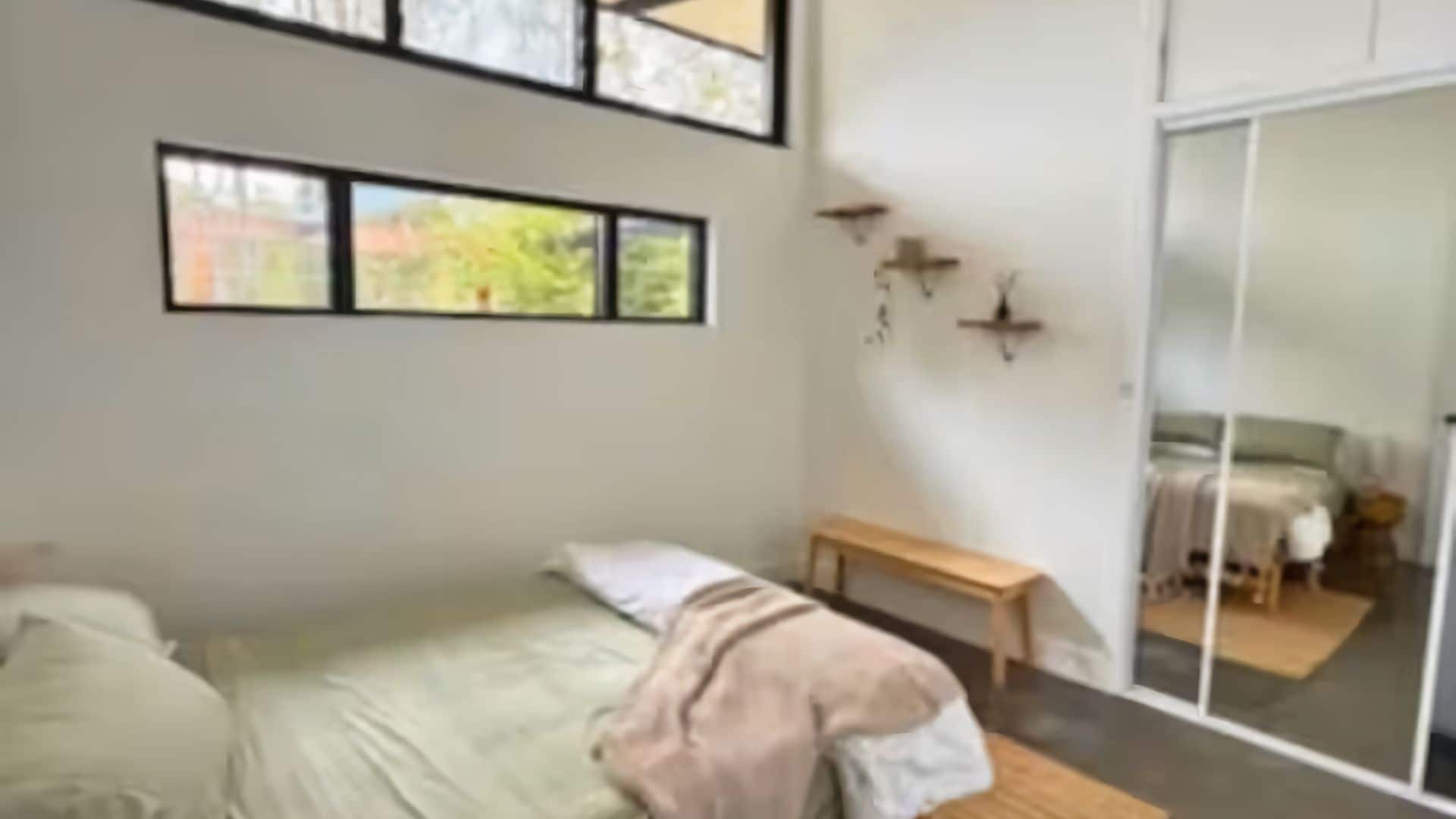 A bedroom with a bed, a bench, and a sliding glass door leading to a balcony.