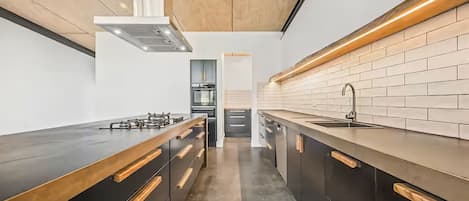 Une cuisine moderne dotée d’un îlot central, de meubles noirs et d’un évier en acier inoxydable.