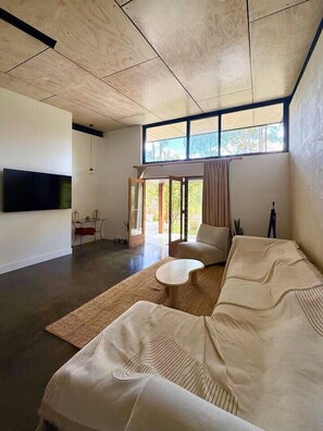 A modern living room with a large sofa, a coffee table, and a flat-screen TV mounted on the wall.