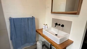 Une salle de bain avec un lavabo blanc, un plan de toilette en bois et une serviette bleue.