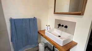 A bathroom with a white sink, wooden countertop, and a blue towel. - Teague Retreat Studio Space (South Kempsey)