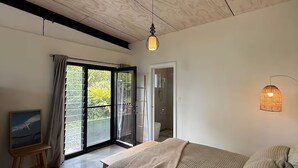Une chambre à coucher avec un lit, un tableau, une fenêtre avec des rideaux et un espace douche.