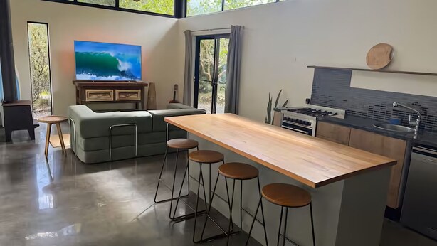 Une cuisine moderne avec un coin bar, des tabourets de bar, un téléviseur et une grande fenêtre.