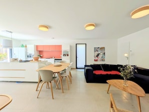 Un espacio habitable moderno con comedor, cocina y un sofá negro con una manta roja.