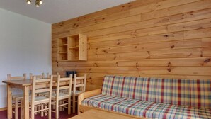 Un interior de madera con un sofá, sillas, una mesa y una estantería de pared.