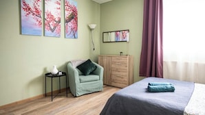 Ein Schlafzimmer mit einem Bett, einem Sessel, einem Schrank und Kunstwerken an der Wand.