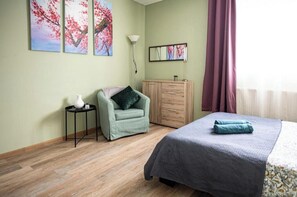 A bedroom with a bed, a chair, a cabinet, and artwork on the wall. - Fanta Flat France Switzerland - Comfort & Quiet near Basel (Saint-Louis)
