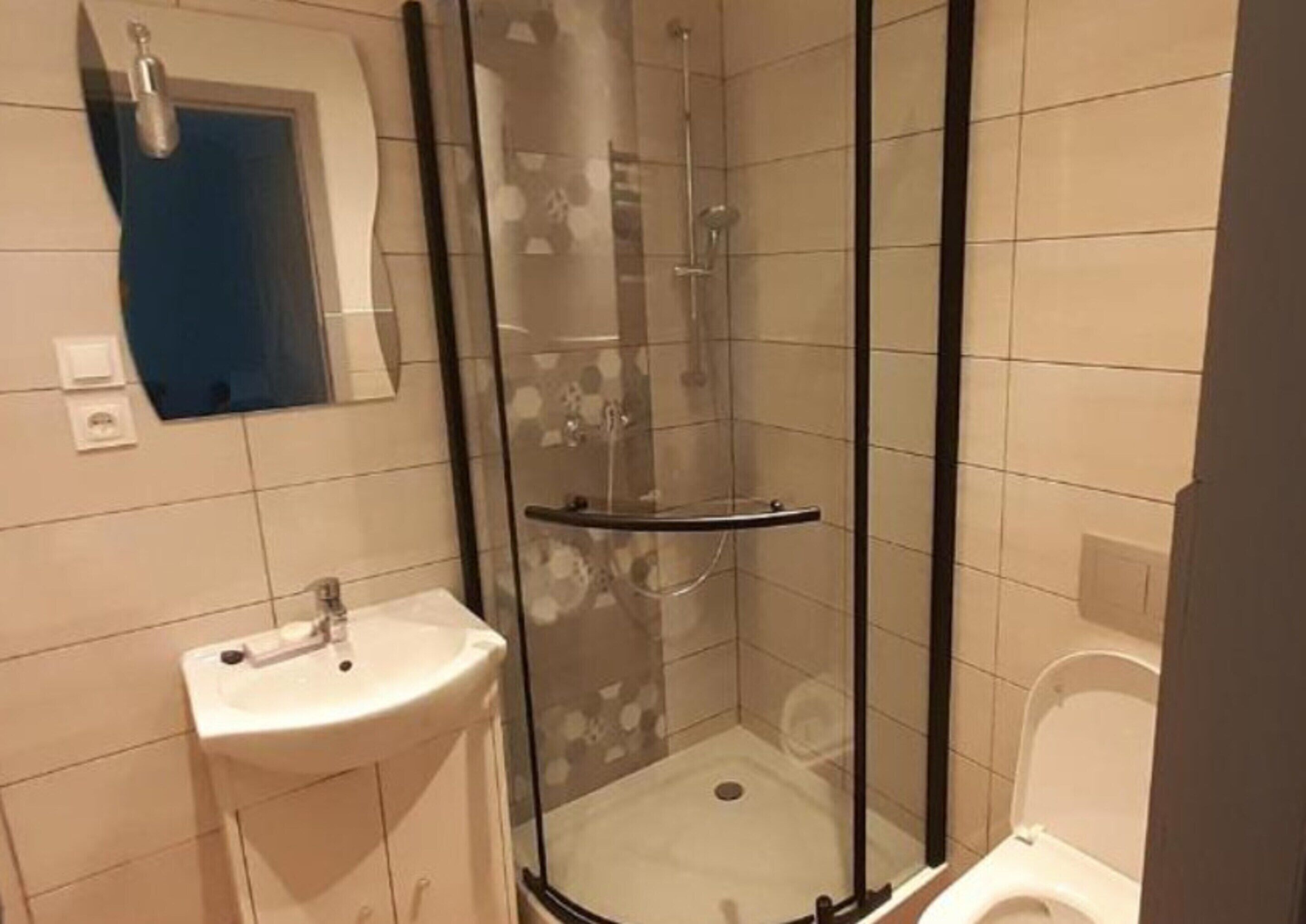A bathroom with a glass-enclosed shower, a sink, and a toilet.