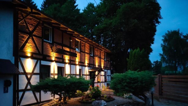 Ein traditionelles Fachwerkhäuschen mit einer gut beleuchteten Fassade und einem angelegten Garten.
