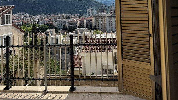 Een balkon met uitzicht op een stadsbeeld en bergen.