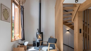 Un interior moderno con chimenea, una silla, una cesta tejida y una escalera.