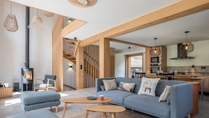 Una sala de estar moderna con un sofá seccional, una chimenea y una cocina al fondo.