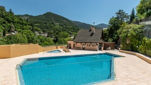 A swimming pool with a view of a mountain and a building with a sloped roof. - Spacious Apartment for 5-persons (Guillaumes)
