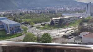 Vista desde una ventana hacia un paisaje urbano con edificios, una carretera y montañas al fondo.