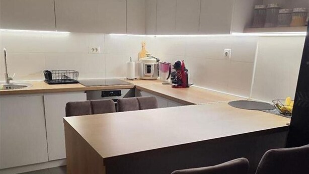 Una cocina moderna con una isla central, taburetes de bar y electrodomésticos integrados.