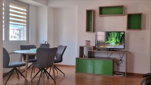 Una sala de estar moderna con comedor, televisor de pantalla plana y un aparador verde.