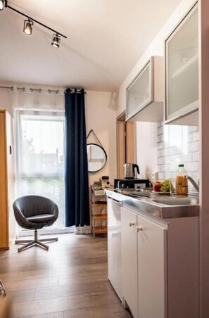 Eine kleine Küche mit Essbereich, einem Stuhl und Blick durch ein Fenster.