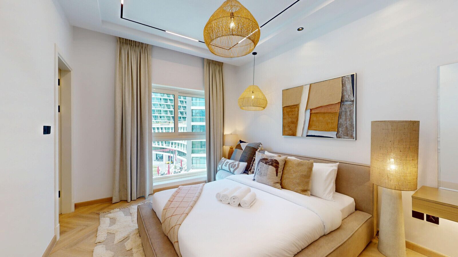 Ein modernes Schlafzimmer mit einem großen Bett, Blick auf eine Stadtlandschaft und einer außergewöhnlichen gewebten Leuchte.