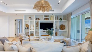 Una sala de estar moderna con un sofá, un televisor y una estantería decorativa con varios objetos.