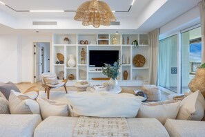 A modern living room with a sofa, a television, and a decorative shelf with various items. - Calm 4 Bed Oasis l Serene Sea View l Palm Jumeirah (Palm Jumeirah)