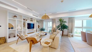 Una sala de estar moderna con un sofá, sillas, un televisor y un ventanal grande.