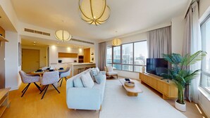 En moderne stue med sofa, spiseområde og fjernsyn.
