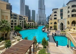 A hotel with a central swimming pool, connected to a smaller pool, surrounded by palm trees and a city skyline in the background. - Aesthetic 1 Bed l Close to Burj Khalifa l Downtown (Downtown Dubai)